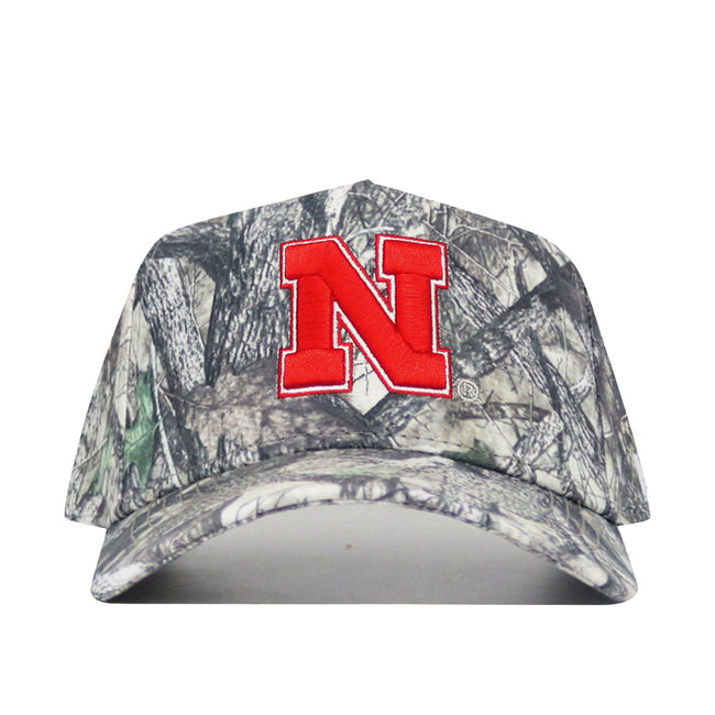 The No Rivals Nebraska Outland Hat is a structured fit camouflage cap, featuring a large red N outlined in white on the front over a tree branch and leaf pattern.