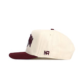 Side view of the Texas A&M Stadium Hat by No Rivals, featuring a cream snapback with maroon brim and button, NR logo embroidery on the side, partial text on front, and structured fit in high-quality cotton.