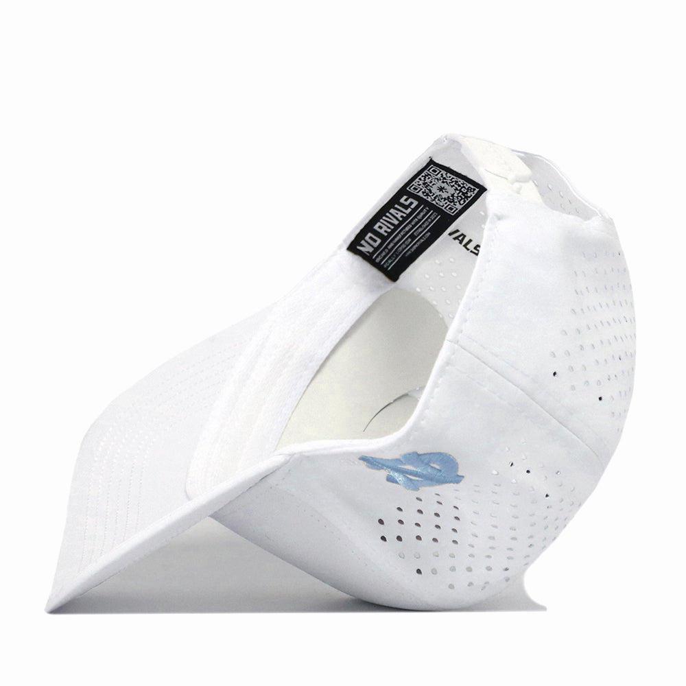 A North Carolina Tar Heels Mascot Hat in white by No Rivals is displayed on its side, highlighting the interior, adjustable strap, and a small blue embroidered logo on the exterior. This hat also features a black label with a QR code attached near the snap back strap.