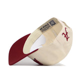 The Alabama Stadium Hat by No Rivals is shown upside down, revealing its NO RIVALS label. This cream and maroon snapback features a maroon embroidered LC logo on the front and offers a structured fit in premium cotton.