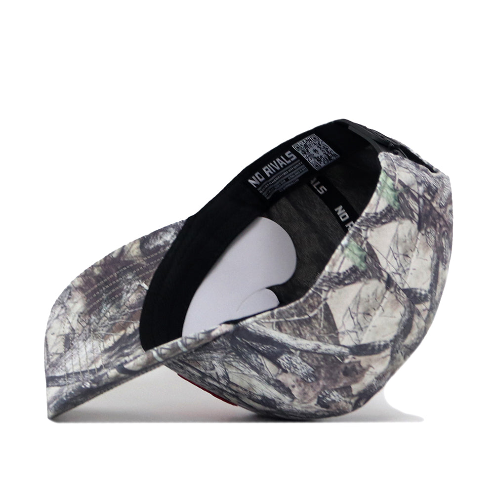 The Wisconsin Badgers Outland Hat by No Rivals features a camouflage pattern and is displayed upside down to show the black inner lining and sweatband, complete with a label and QR code inside. Its classic gameday fit is complemented by a comfortable snap back adjustment, while an embroidered logo offers a subtle touch of style.