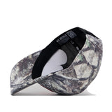 The Wisconsin Badgers Outland Hat by No Rivals features a camouflage pattern and is displayed upside down to show the black inner lining and sweatband, complete with a label and QR code inside. Its classic gameday fit is complemented by a comfortable snap back adjustment, while an embroidered logo offers a subtle touch of style.