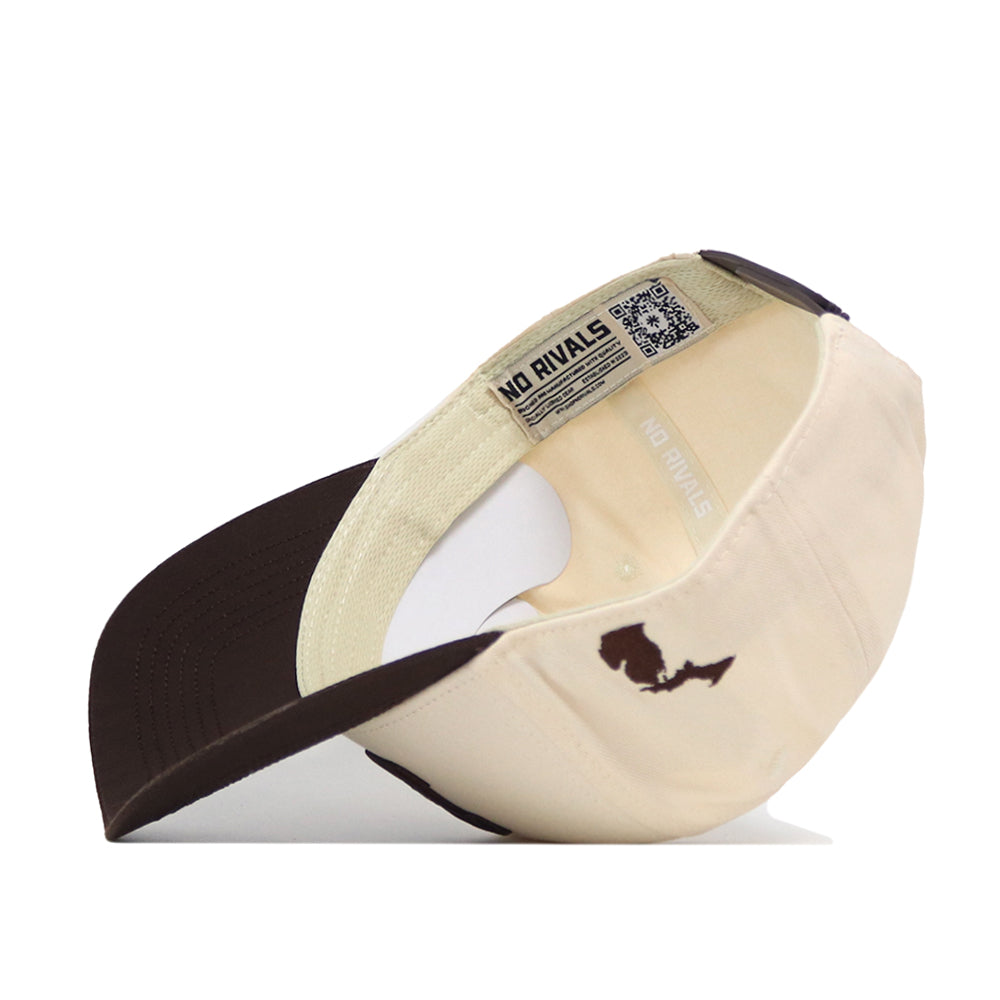 The Michigan Wolverines Espresso Hat by No Rivals is displayed upside down, showcasing its inner label that reads NO RIVALS and a small, dark embroidered map design on the side near the back. This officially licensed cap also features a classic snapback closure for an adjustable fit.