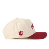 Introducing the Right Side Up Indiana Hat - Classic Colors by No Rivals. This officially licensed cap features a cream-colored snapback design with a bold red brim and an IU embroidered logo stitched on the side, proudly representing Indiana University. Red lettering is partially visible from this side view, adding to its distinctive style.