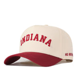 The Right Side Up Indiana Hat - Classic Colors by No Rivals is a cream-colored baseball cap made from high-quality cotton. It features “INDIANA” embroidered in red on the front and “NO RIVAL” stitched in red on the side of the red brim, with an adjustable snap back closure for a perfect fit.