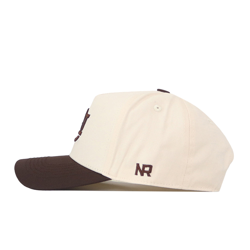 A side view of the Auburn Espresso Hat by No Rivals, featuring a cream crown with a brown brim. This stylish snapback has “NR” embroidered in brown near the back, making it an ideal gameday fit for any fan.