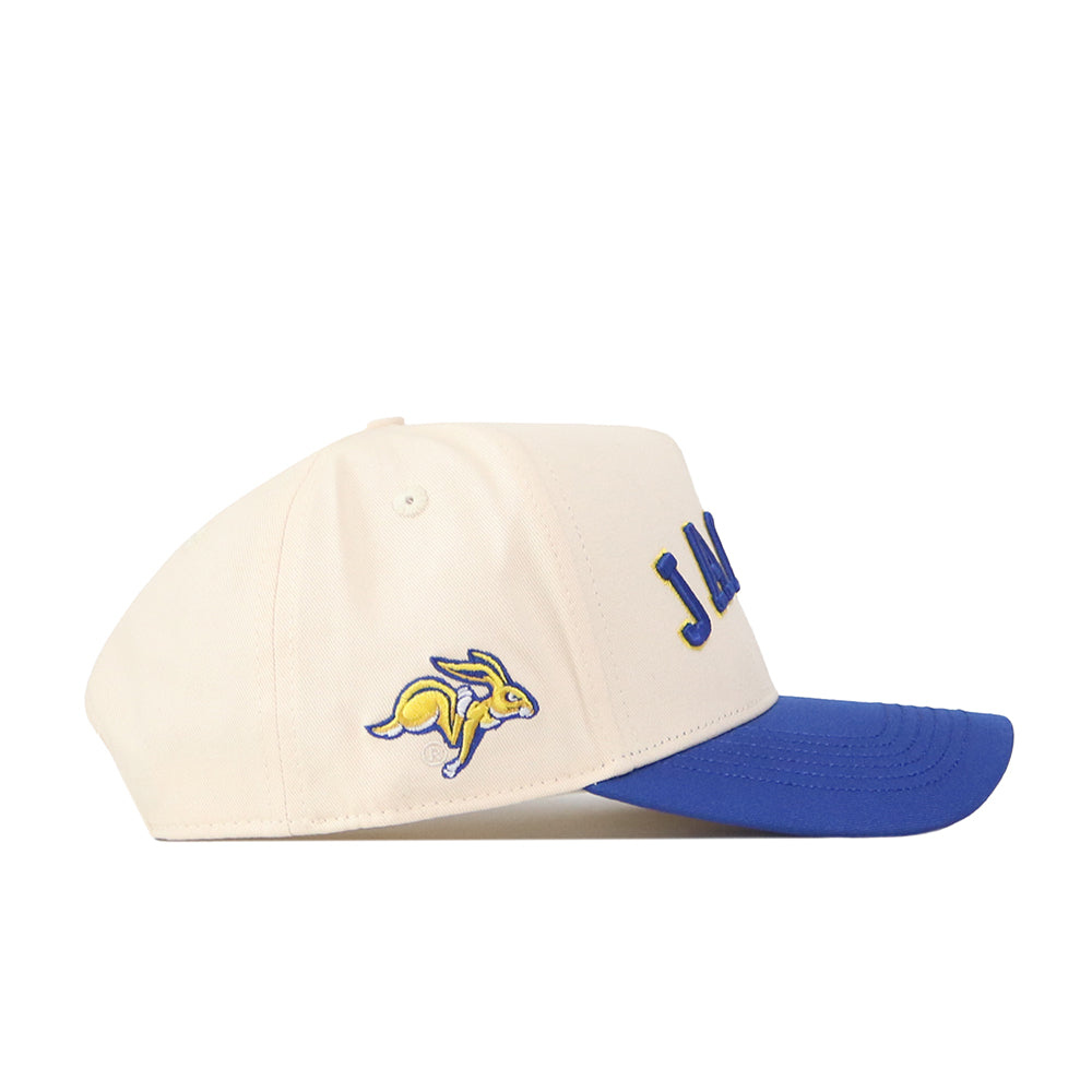 The Right Side Up Jacks Hat - Classic by No Rivals is a cream-colored South Dakota State Jackrabbits snapback with a blue brim, bold blue lettering on the front, and an embroidered yellow and blue rabbit logo on the side. It features an adjustable closure for a comfortable fit.