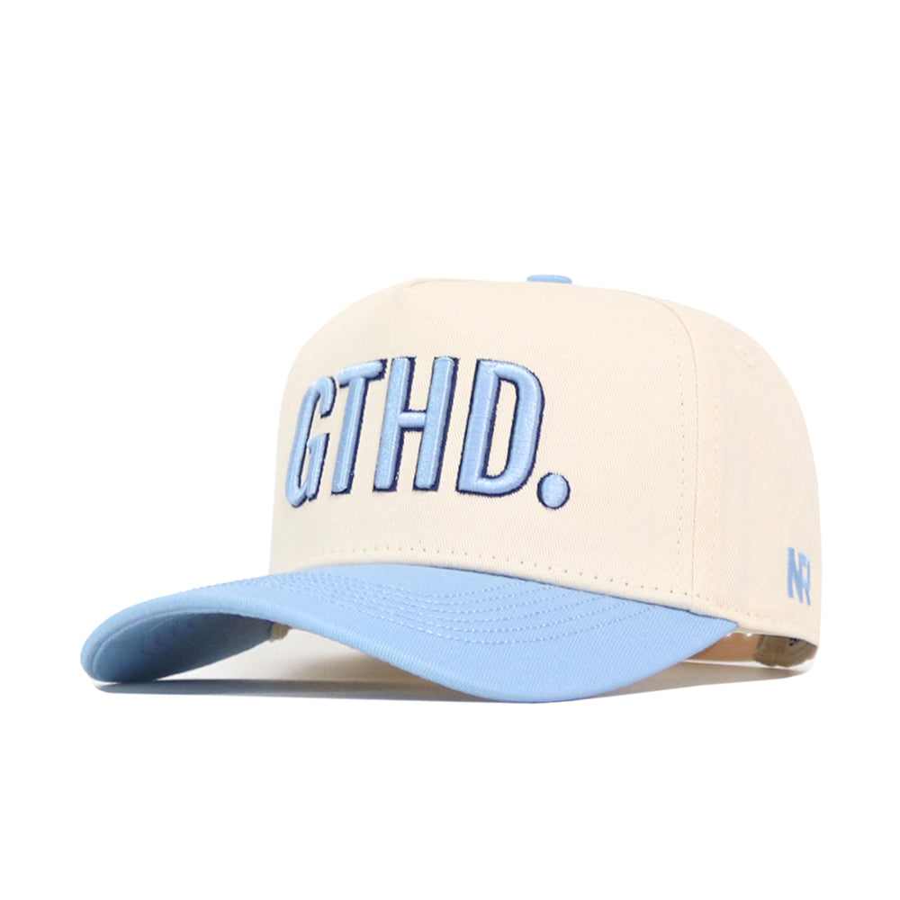The No Rivals GTHD Hat features a beige snapback design with a light blue brim, bold raised blue GTHD. letters on the front, and a small embroidered NF logo on the side.