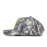 A side view of the Michigan Wolverines Outland Hat by No Rivals, a camouflage baseball cap with a yellow rectangle on the front, “NR” white embroidered letters on the side, and a Snap Back Adjustment for a comfortable Gameday Fit, shown against a plain white background.