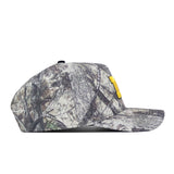 Side view of the No Rivals Michigan Wolverines Outland Hat, a camouflage snapback baseball cap with a flat brim and a yellow rectangular patch above the brim, featuring an officially licensed embroidered Michigan Wolverines logo, photographed on a white background.