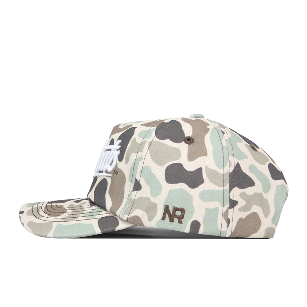 The Sam Houston State Huntsman Hat by No Rivals is a camouflage-patterned baseball cap made from high-quality cotton, showcasing crisp white “Sam Houston State” lettering on the front and a brown embroidered No Rivals (NR) logo on the side, displayed in a left side profile view.