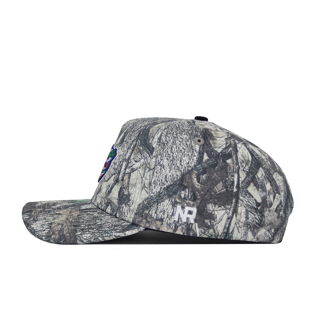 A side view of the No Rivals University of Florida Outland Hat highlights its camo-patterned, structured fit with a flat brim, white NR initials embroidered on the side, and a partially visible colorful patch on the front.