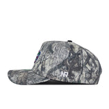A side view of the No Rivals University of Florida Outland Hat highlights its camo-patterned, structured fit with a flat brim, white NR initials embroidered on the side, and a partially visible colorful patch on the front.