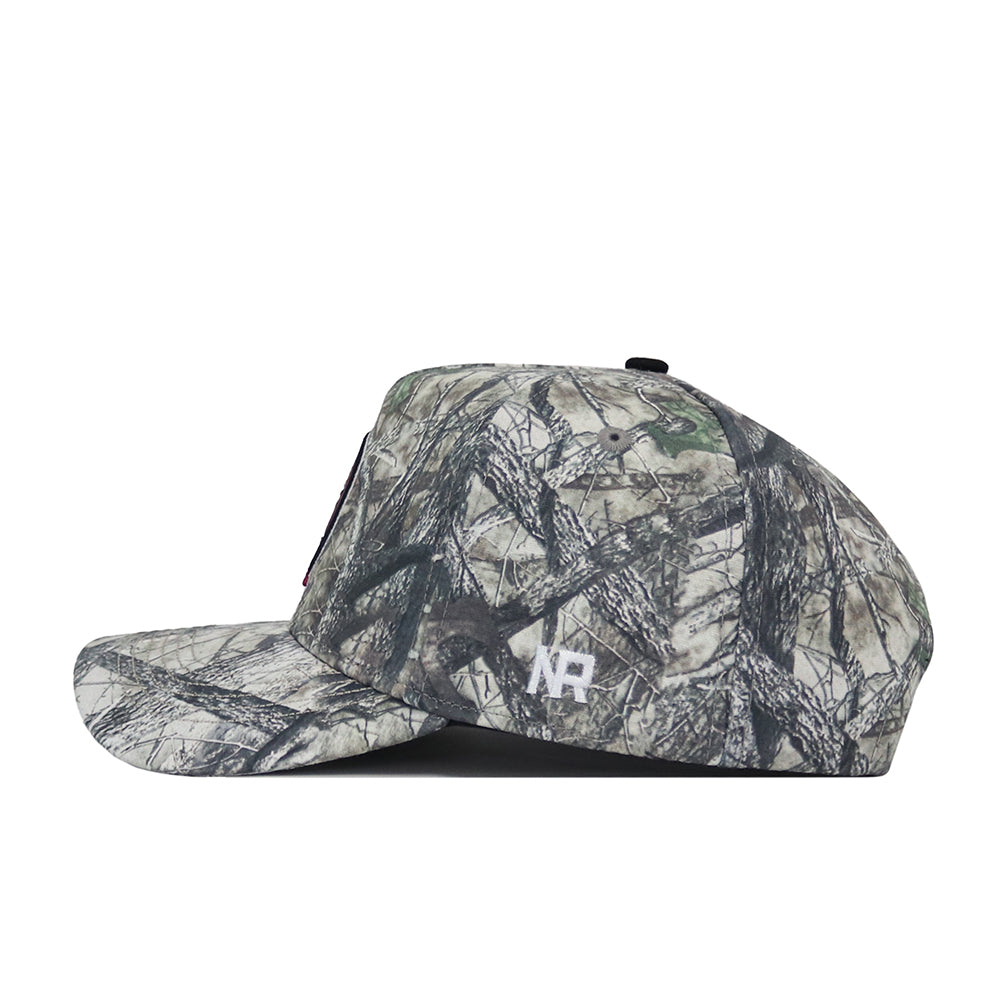A side view of the No Rivals Florida State Outland Hat, a structured fit flat-brim cap in woodland camouflage with white NR initials embroidered on the side, crafted from high quality cotton.