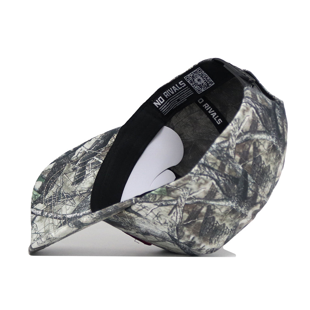 A Virginia Tech Outland Hat by No Rivals, featuring a camouflage pattern, is displayed on its side to reveal “NO RIVALS” along the inner band and a QR code under the brim, set against a plain white background.