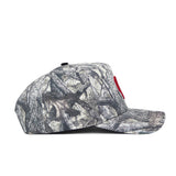 A side view of the No Rivals Oklahoma Outland Hat, a structured snapback in a gray and brown tree branch camo. Made from high-quality cotton, it features a small red accent on the front.