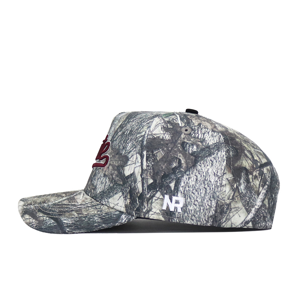 A side view of the Mississippi State Outland Hat by No Rivals, a woodland camouflage snapback with a red embroidered logo on the front, white NR initials on the side, high-quality cotton, and a curved brim.