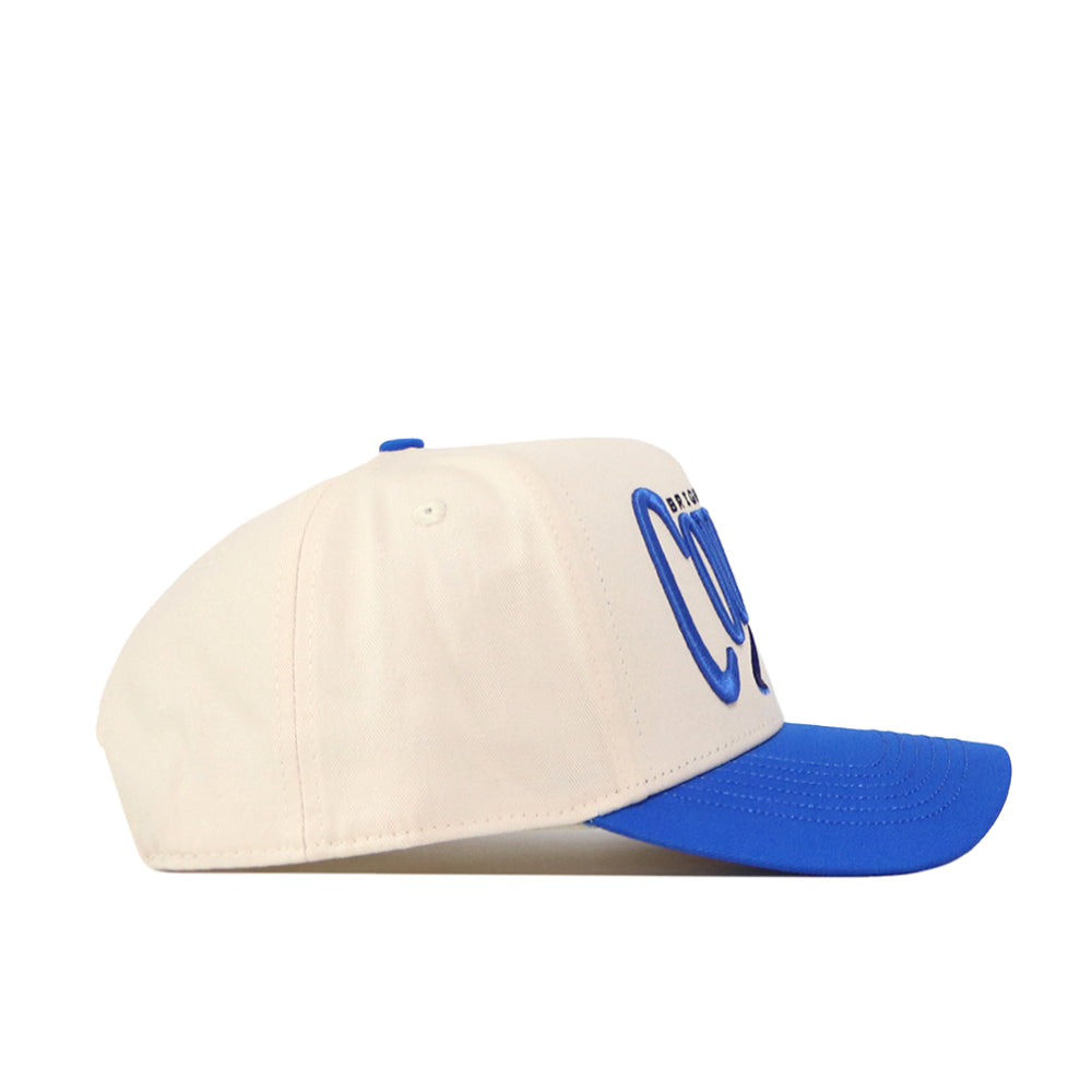 The BYU Cougars Stride Hat by No Rivals features a cream-colored snapback design with a blue brim and raised blue embroidered logos on the front, pictured in a left-side profile view against a plain white background—the perfect finishing touch for your gameday fit.