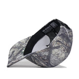 The Baylor Outland Hat by No Rivals is shown upside down, revealing an inside label that reads “NO RIVALS” and a QR code on the black internal band. Made from high-quality cotton, this cap features a grey and green camo pattern with a classic snapback closure.