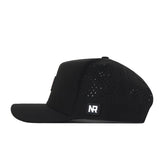 Introducing the Wisconsin Badgers Trainer Hat by No Rivals—a black snapback cap featuring a structured fit, flat brim, and side ventilation holes. Made from durable cotton material, it showcases a small rectangular NR logo patch on the side. The hat is presented in a side profile against a white background.