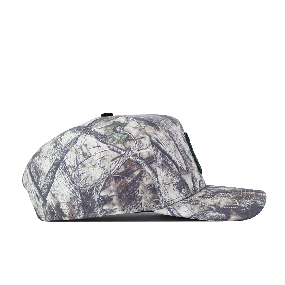 Side view of the No Rivals Charlotte Outland Hat, a camouflage baseball cap with a flat brim, featuring a pattern of gray, green, and brown tones reminiscent of tree branches and leaves. The embroidered logo on the front adds a standout touch to your gameday fit, while the snap back adjustment ensures a comfortable and customizable fit.