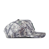 Side view of the No Rivals Charlotte Outland Hat, a camouflage baseball cap with a flat brim, featuring a pattern of gray, green, and brown tones reminiscent of tree branches and leaves. The embroidered logo on the front adds a standout touch to your gameday fit, while the snap back adjustment ensures a comfortable and customizable fit.