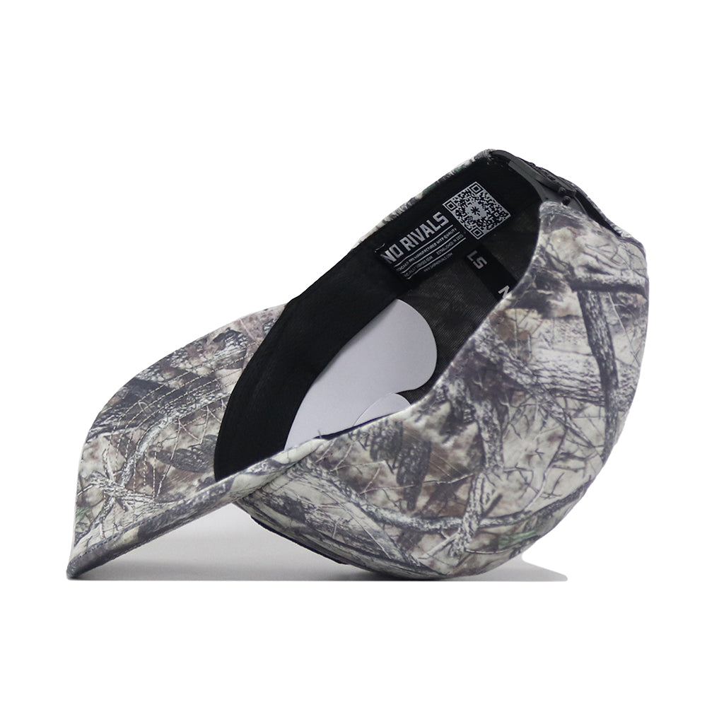 A side view of the Charlotte Outland Hat by No Rivals is shown resting on its brim, with the inside label and tag visible. Featuring a curved bill and a convenient Snap Back Adjustment for a perfect fit, this camouflage-patterned cap offers both style and comfort for your Gameday Fit.
