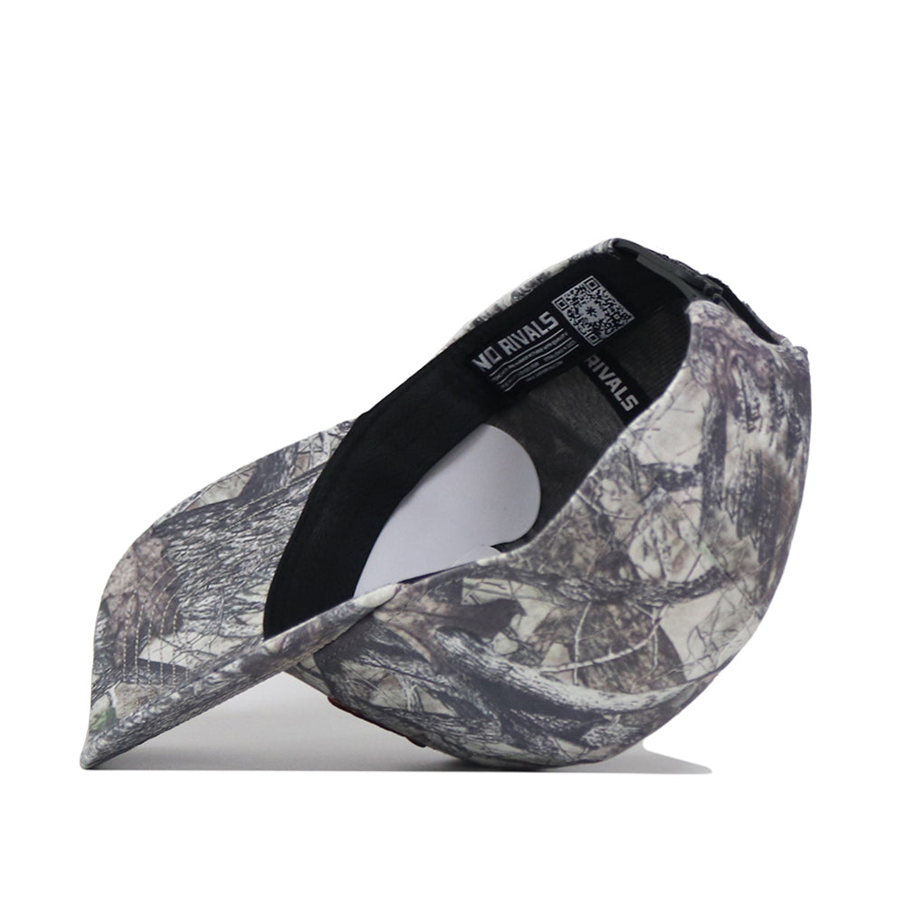 A camouflage baseball cap is shown inside out, displaying the interior tag, stitching details, and an embroidered logo against a white background.