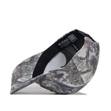 A camouflage baseball cap is shown inside out, displaying the interior tag, stitching details, and an embroidered logo against a white background.
