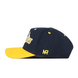 Show off your perfect Gameday Fit with the Michigan Wolverines Boomerang Hat by No Rivals—a navy blue snapback cap featuring a yellow brim and a yellow embroidered NR logo on the side, displayed in a stylish side profile view.