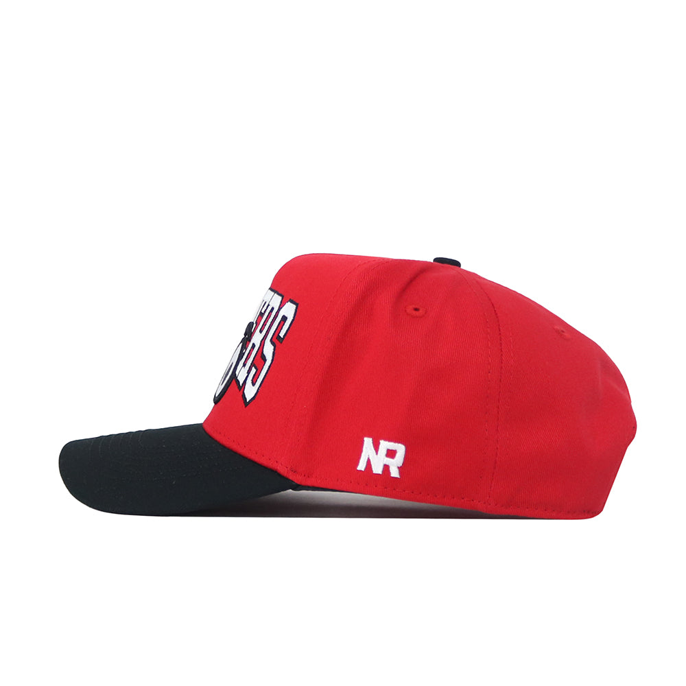 The WKU Toppers Big Red Eyes Hat by No Rivals is a high-quality cotton red snapback with a black curved brim, white and black embroidered front text, and “NR” in white on the side, shown here in a side profile.