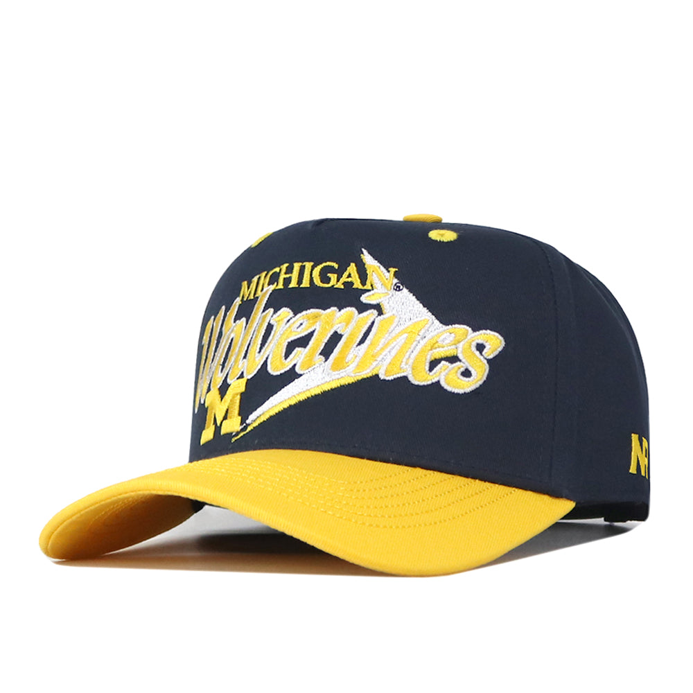 The No Rivals Michigan Wolverines Boomerang Hat is an officially licensed navy blue and yellow baseball cap featuring a large embroidered M logo on the front, a vibrant yellow brim, distinctive accents, and a convenient snap back closure for an adjustable fit.