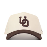 The Oregon Espresso Hat by No Rivals features a cream snapback design with a dark brown brim and an embroidered overlapping UO logo in dark brown—perfect for your next Gameday Fit.