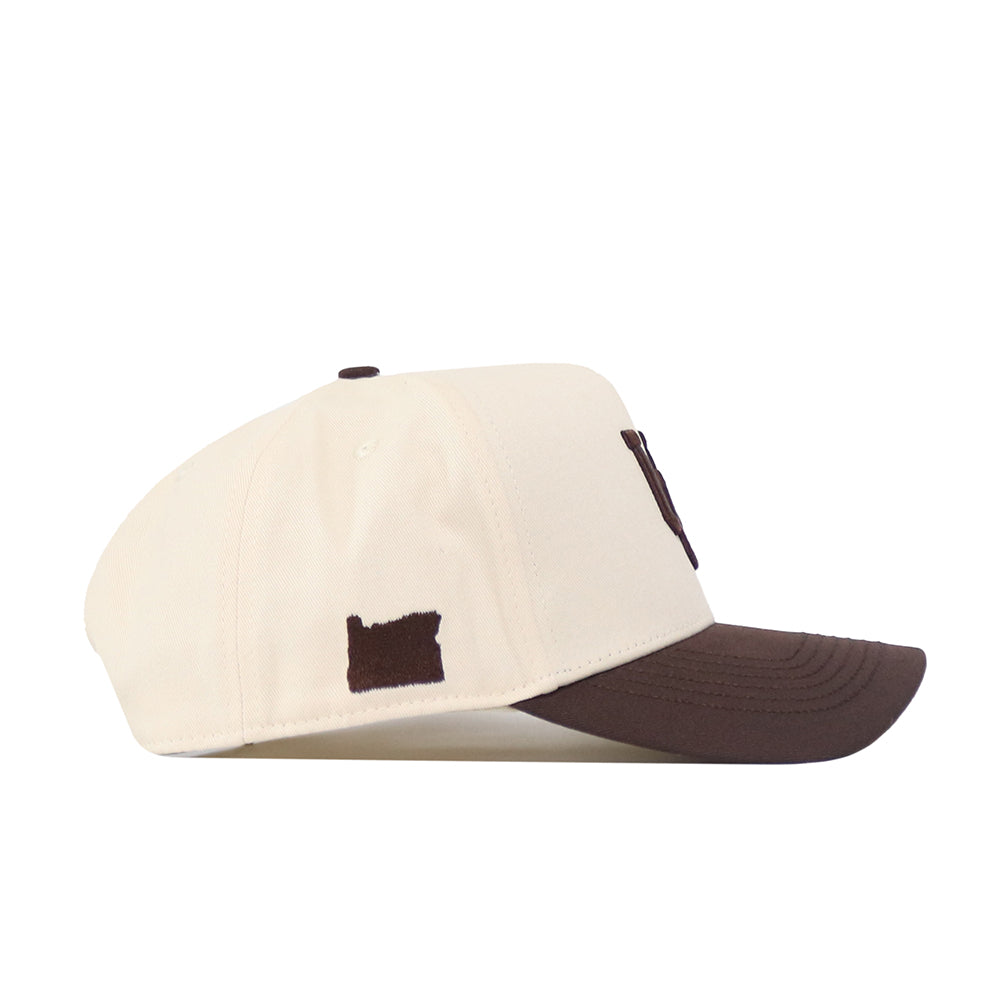 The Oregon Espresso Hat by No Rivals features a cream snapback design with a dark brown brim and an embroidered state logo on the side—an ideal pick for your next gameday look.