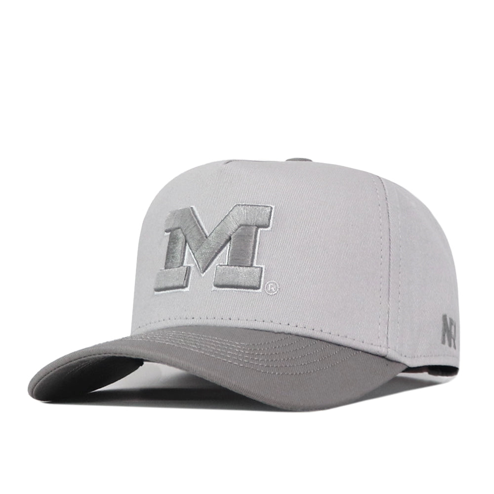 The Michigan Wolverines Graphite Hat by No Rivals features a light gray design with a raised, embroidered “M” on the front and a slightly curved brim. Its snapback closure ensures a comfortable fit, while smaller embroidered letters decorate the side—making it perfect for completing your gameday look.