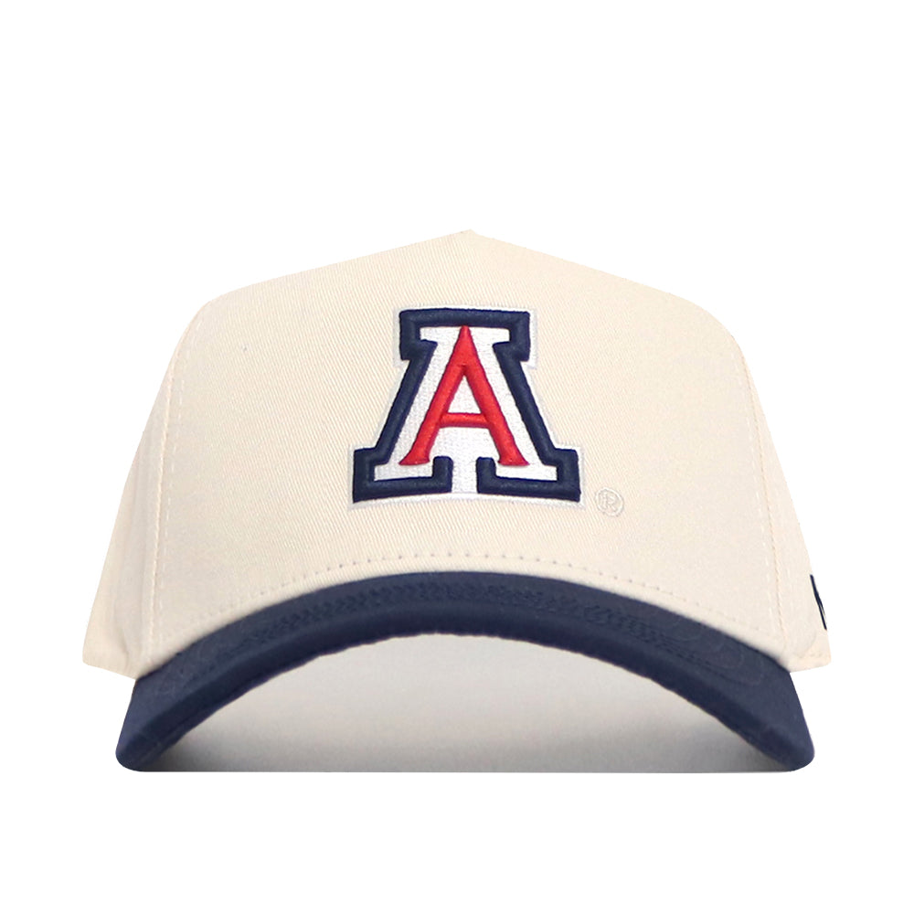 The Arizona Logo Patch Hat by No Rivals is a cream snapback with a navy brim, featuring a bold 3D red, white, and blue "A" on the front. Officially licensed for authentic style.