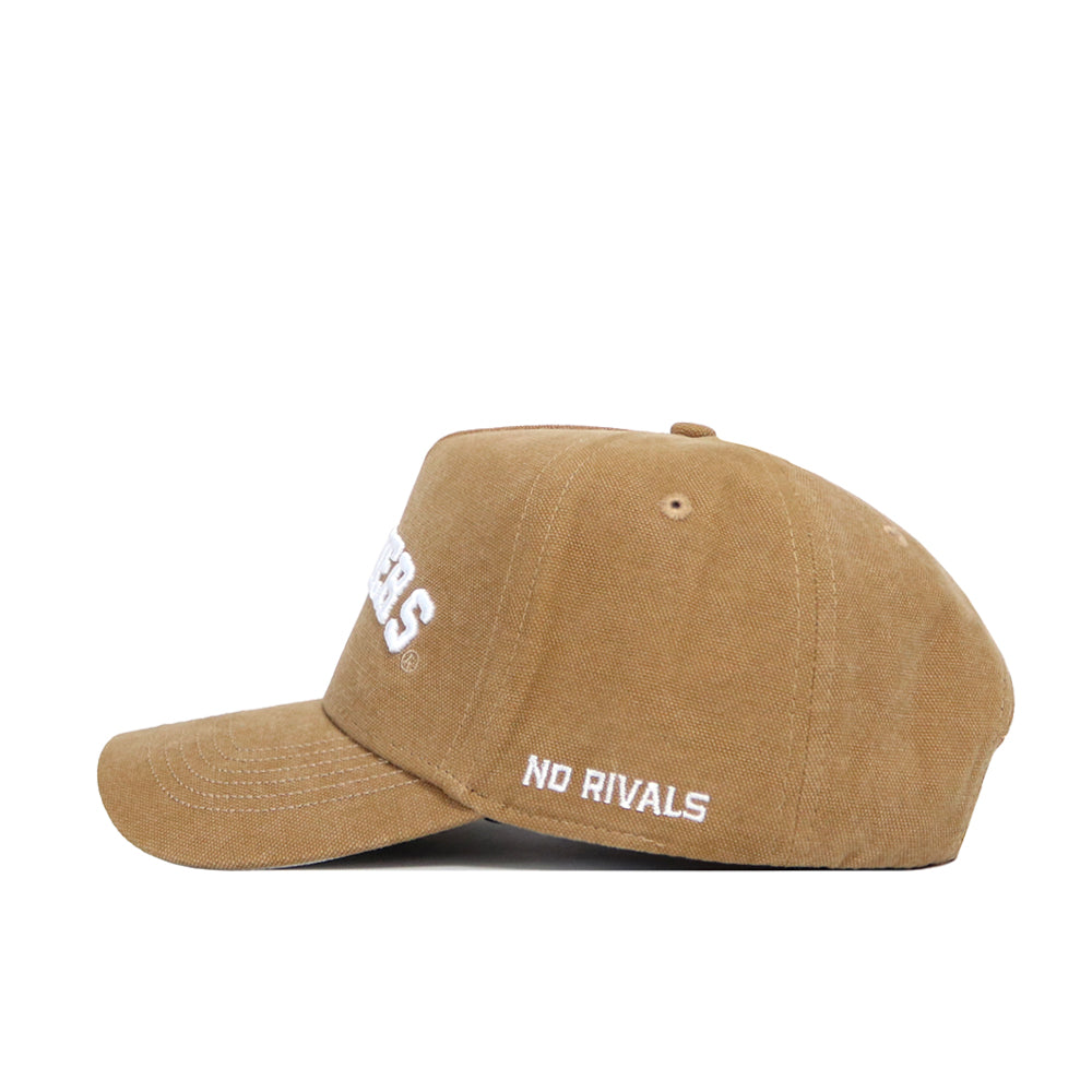 The Indiana Rustic Hat by No Rivals is a brown cotton canvas baseball cap with white NO RIVALS embroidery on the side and an adjustable snapback. Shown in side profile against a white background.
