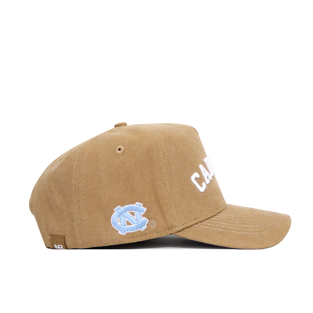 The No Rivals North Carolina Rustic Hat is a brown cotton canvas cap with a curved brim, white embroidered "C.A.R." on the front, and a light blue logo on the side. Displayed in a left side profile view, it offers a structured fit.