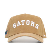 The No Rivals Florida Rustic Hat is a tan cotton canvas cap with "GATORS" embroidered in white on the front, a small multicolored patch on the left side, a slightly curved brim, and a structured fit for lasting style.