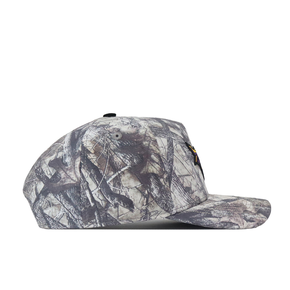 The Minnesota State University Mankato Outland Hat by No Rivals is displayed in profile, facing left, against a white background. This camouflage-patterned baseball cap features an embroidered logo and a stylish snap back design, making it the perfect choice for gameday.