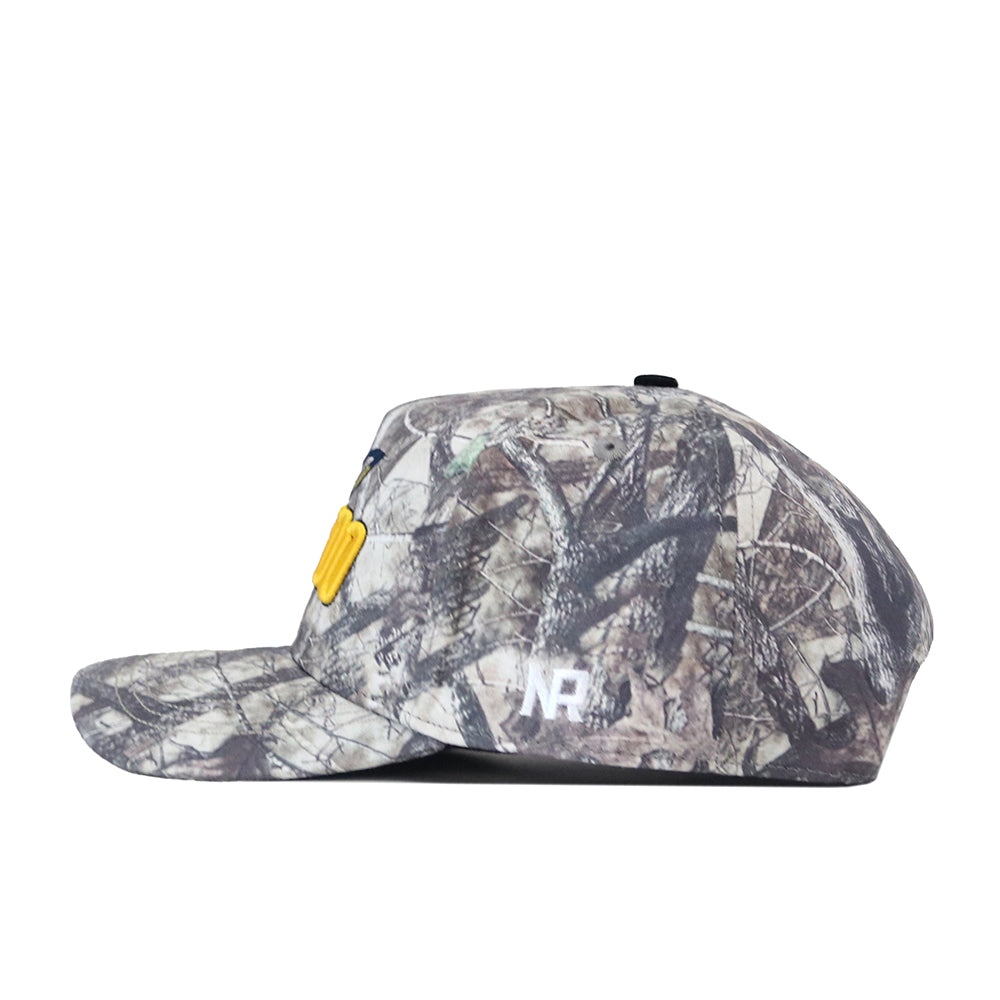 The No Rivals Toledo Outland Hat is shown from the side, featuring a camouflage pattern with a yellow patch on the front and a small white embroidered No Rivals logo on the side. This structured snapback offers customizable comfort with its adjustable flat-brim design.