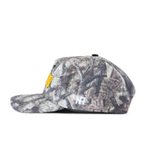 The No Rivals Toledo Outland Hat is shown from the side, featuring a camouflage pattern with a yellow patch on the front and a small white embroidered No Rivals logo on the side. This structured snapback offers customizable comfort with its adjustable flat-brim design.
