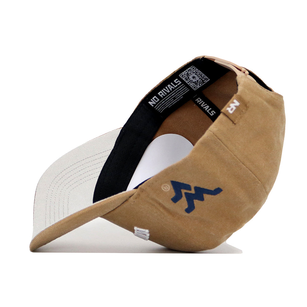 The West Virginia Rustic Hat by No Rivals is a tan and white cotton canvas adjustable cap. Shown on its side, it reveals the underside of the brim, an interior NO RIVALS label, and a blue zigzag logo on the outer side.