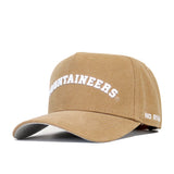 The West Virginia Rustic Hat by No Rivals is a tan cotton canvas cap with "MOUNTAINEERS" embroidered in white on the front and "NO RIV." on the side. It has an adjustable fit, a curved brim, and structured panels for a classic style.