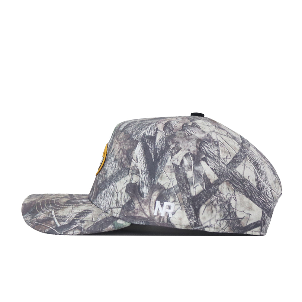 Side view of the No Rivals Mizzou Outland Hat, a flat-brimmed baseball cap with a camouflage pattern, featuring a yellow patch on the front and an embroidered NR logo on the side. Designed with a structured fit and snap back adjustment for customizable comfort.