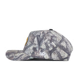 Side view of the No Rivals Mizzou Outland Hat, a flat-brimmed baseball cap with a camouflage pattern, featuring a yellow patch on the front and an embroidered NR logo on the side. Designed with a structured fit and snap back adjustment for customizable comfort.