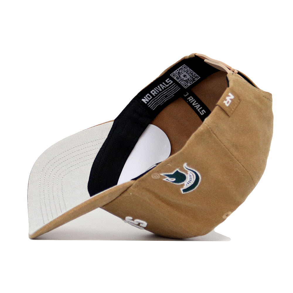 The Michigan State Rustic Hat by No Rivals is a tan cotton canvas cap with white stitching, a gray underbill, and an embroidered green and white mascot logo. It features a structured fit, interior black band, label details, and snap back adjustment.