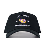 Introducing the LSU Outlaw Hat - Black by No Rivals: This black baseball cap features “LSU TIGERS 1860 BATON ROUGE, LA” embroidered in white, along with a striking tiger’s eye logo in yellow and purple on the front. Designed with a snapback closure, it’s perfect for a comfortable gameday fit.