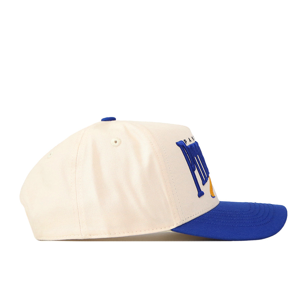 The Pittsburgh Panthers Stride Hat by No Rivals is a cream-colored baseball cap with a blue brim, seen from the side and featuring raised blue and yellow embroidered text on the front panel. Crafted from high-quality cotton, this snapback hat delivers a structured fit for lasting comfort and style.