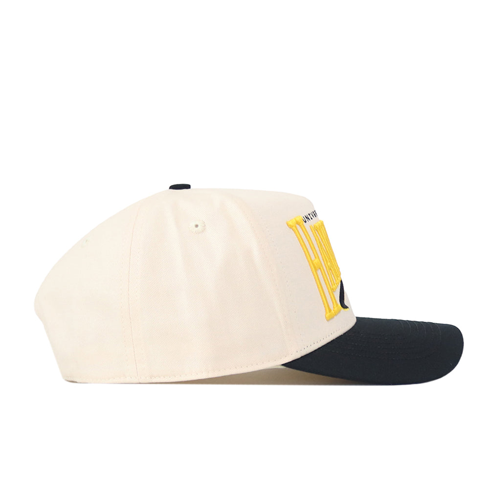 The Iowa Hawkeyes Stride Hat by No Rivals is a beige baseball cap with a black brim and bold yellow lettering on the front, made from high-quality cotton and designed with a structured fit, shown in profile against a white background.